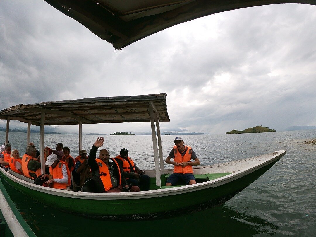 Africa Green Tours guests and guide aboard a wooden boat on Lake Kivu.