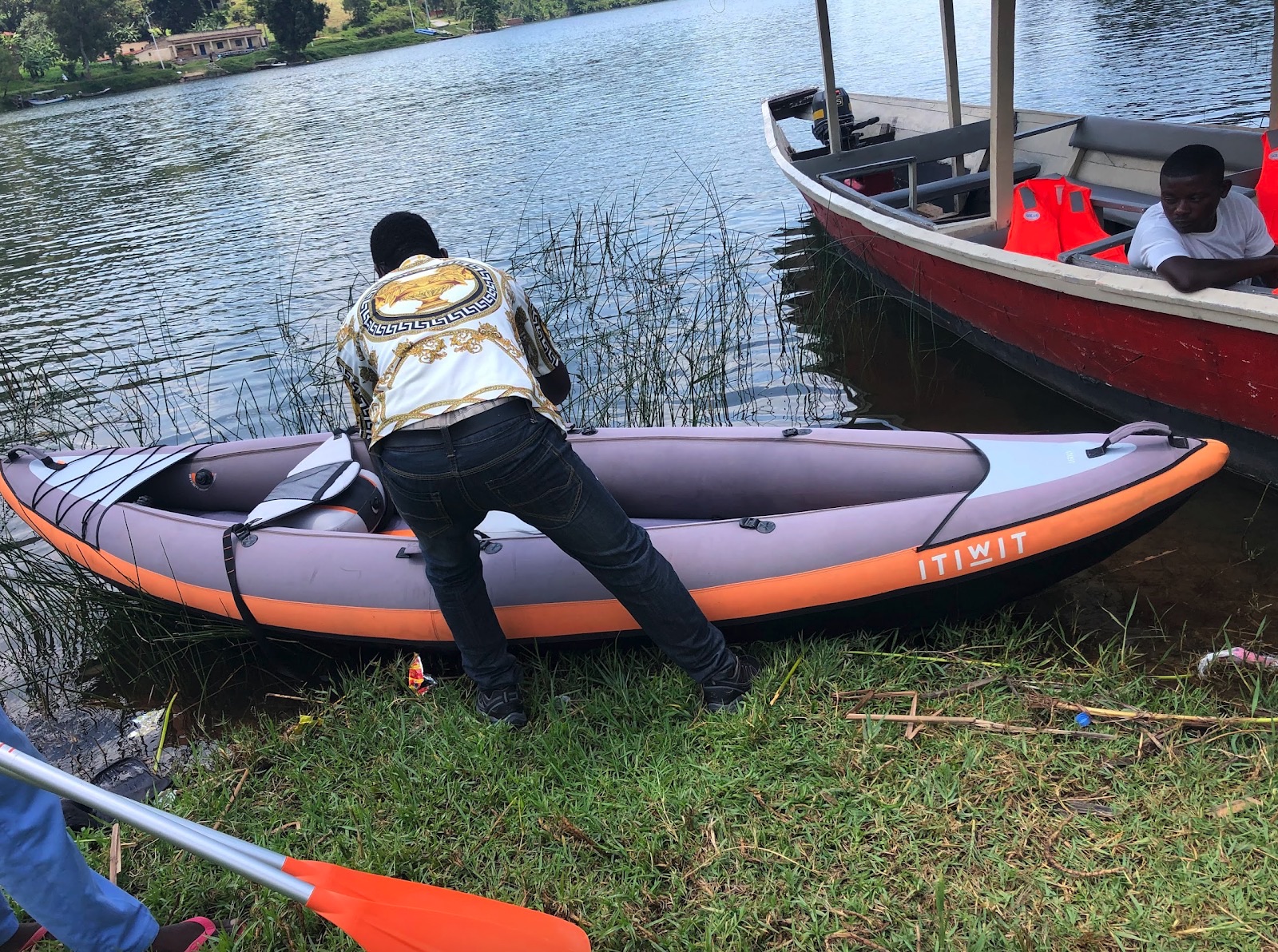 An inflatable canoe on Lake Kivu, ready for paddling along the wooded shore.