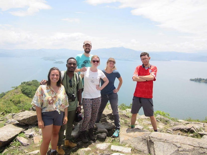 Africa Green Tours guests and guide at a rocky viewpoint overlooking Lake Kivu.