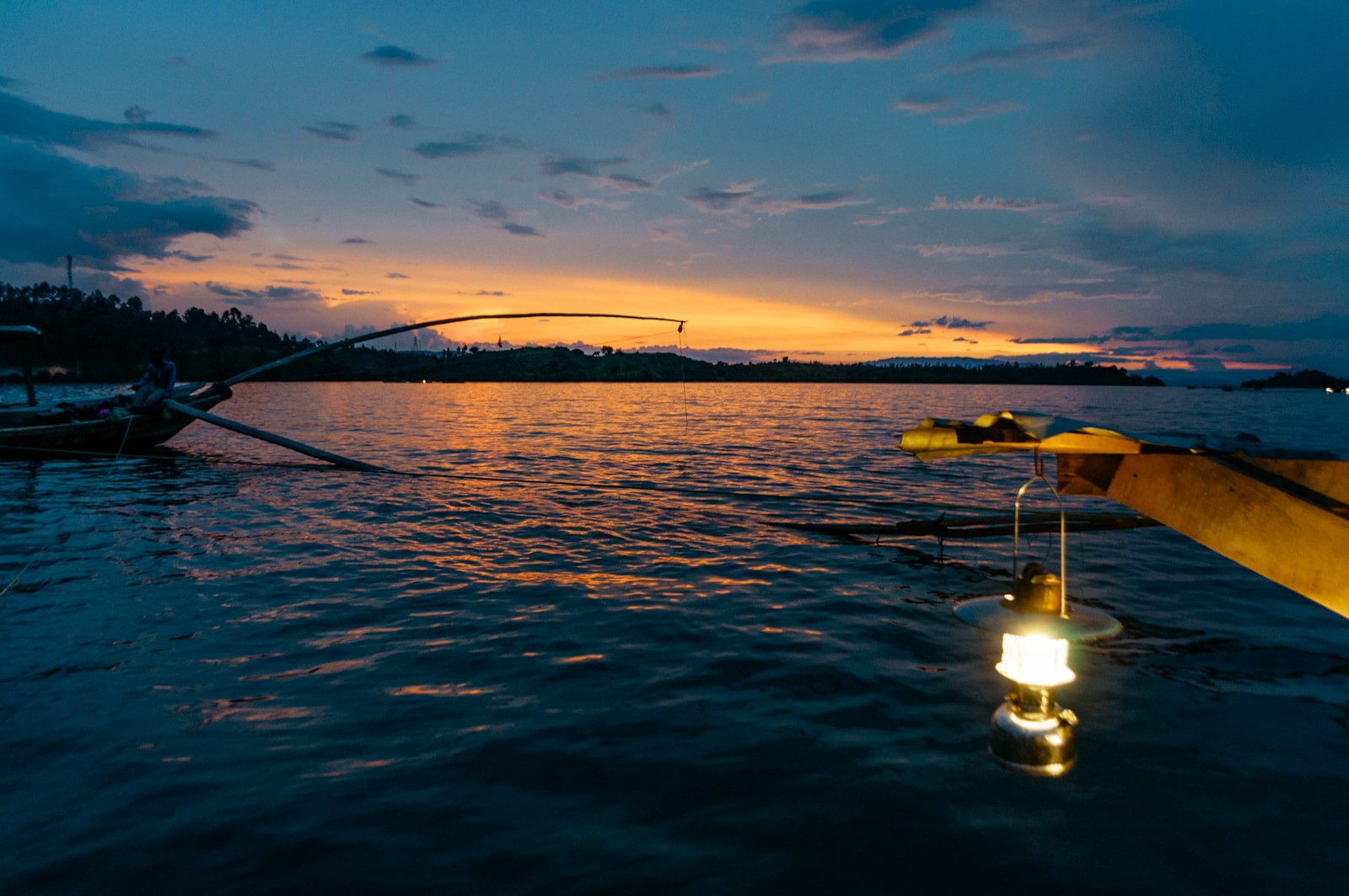 Fishing boats on Lake Kivu at dusk, lit by a lantern.