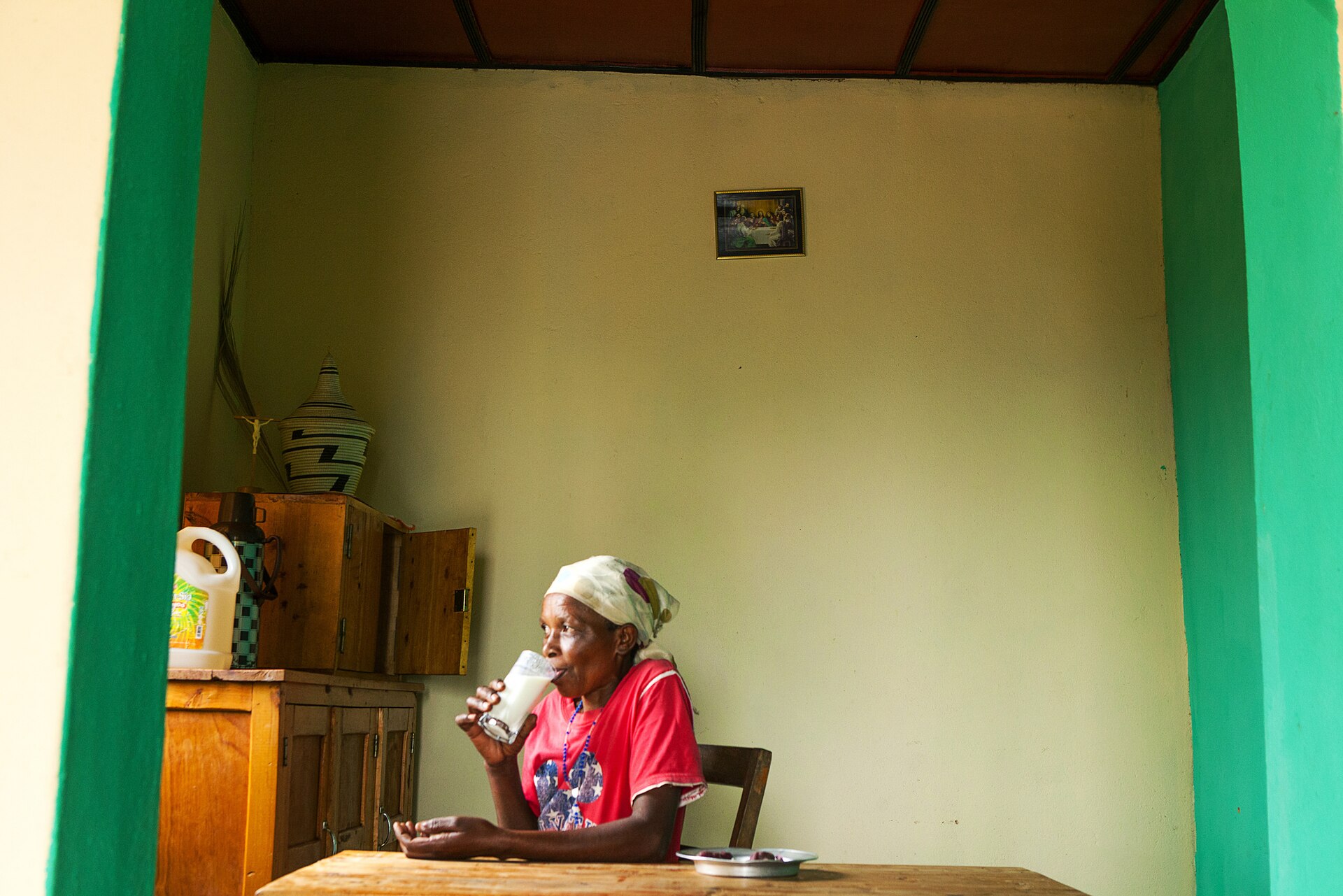 A coffee farmer in Rwanda at home with the result of her cooperative's dairy program.